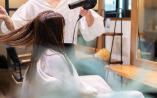 美容室で髪を乾かしてもらう女性