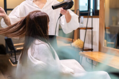 美容室で髪を乾かしてもらう女性